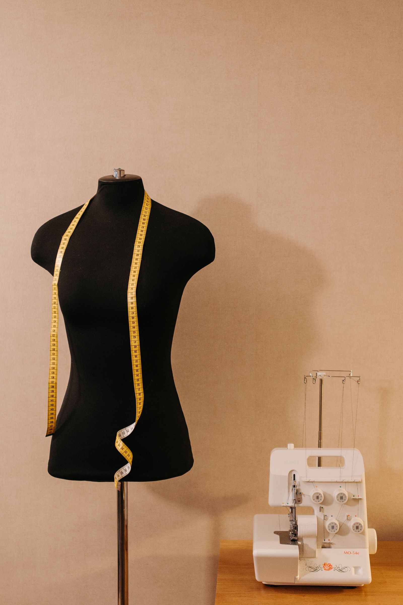 Schneiderbüste mit Maßband und Overlock-Maschine im Atelier